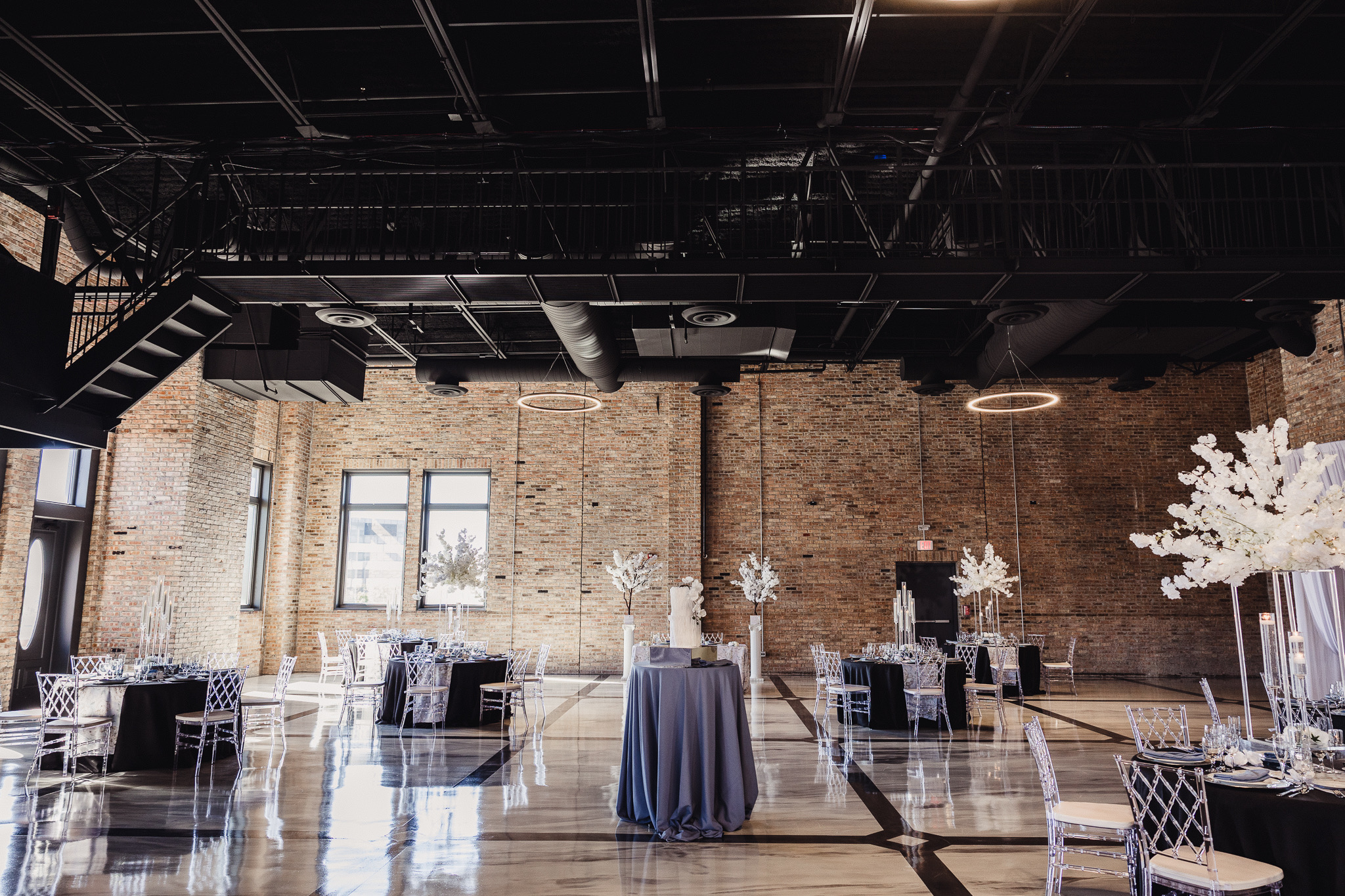 The 1100EventZ hall set for an event, with exposed brick, black steel trusses, and halo lights